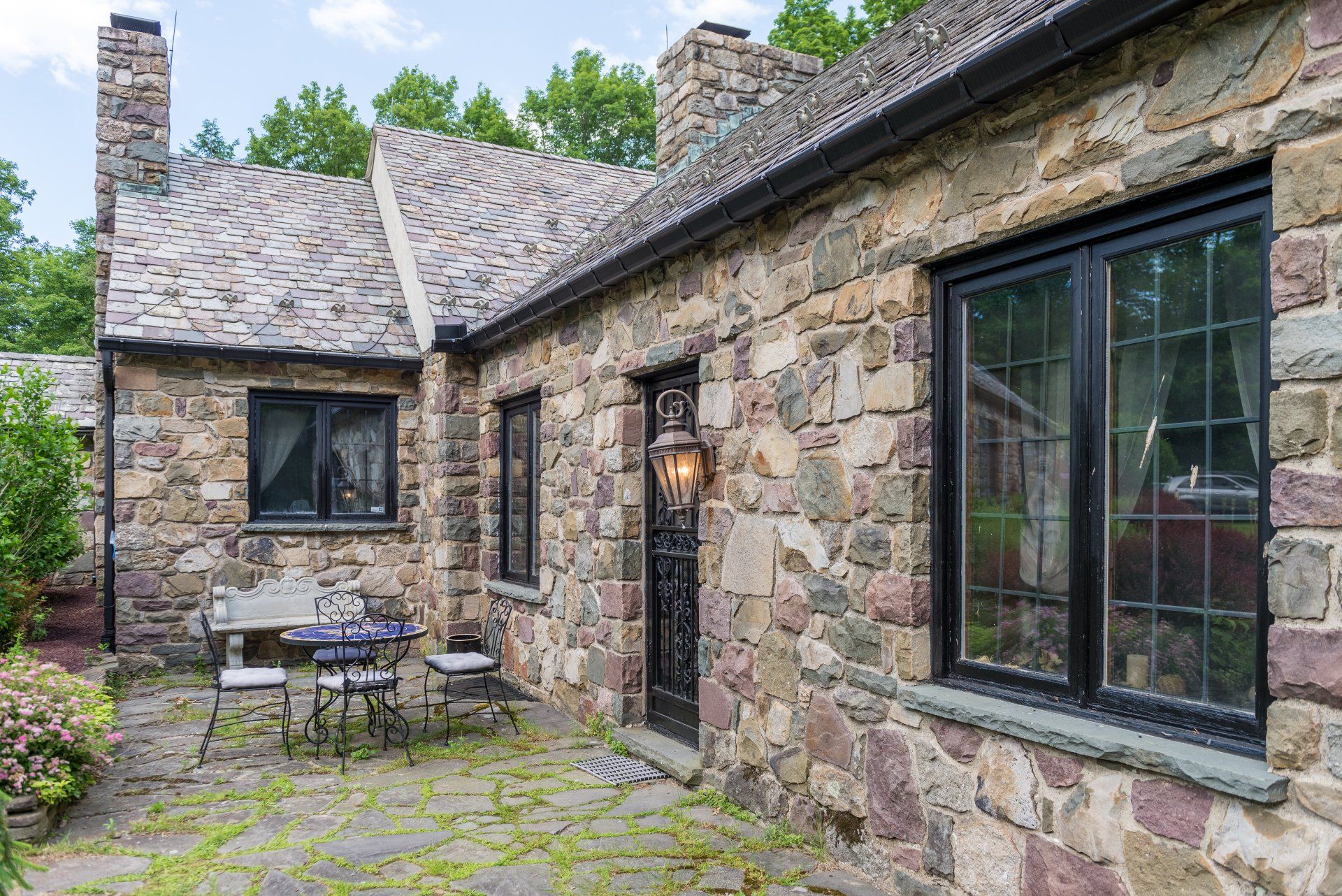 A stone house with a patio and a table and chairs in front of it.