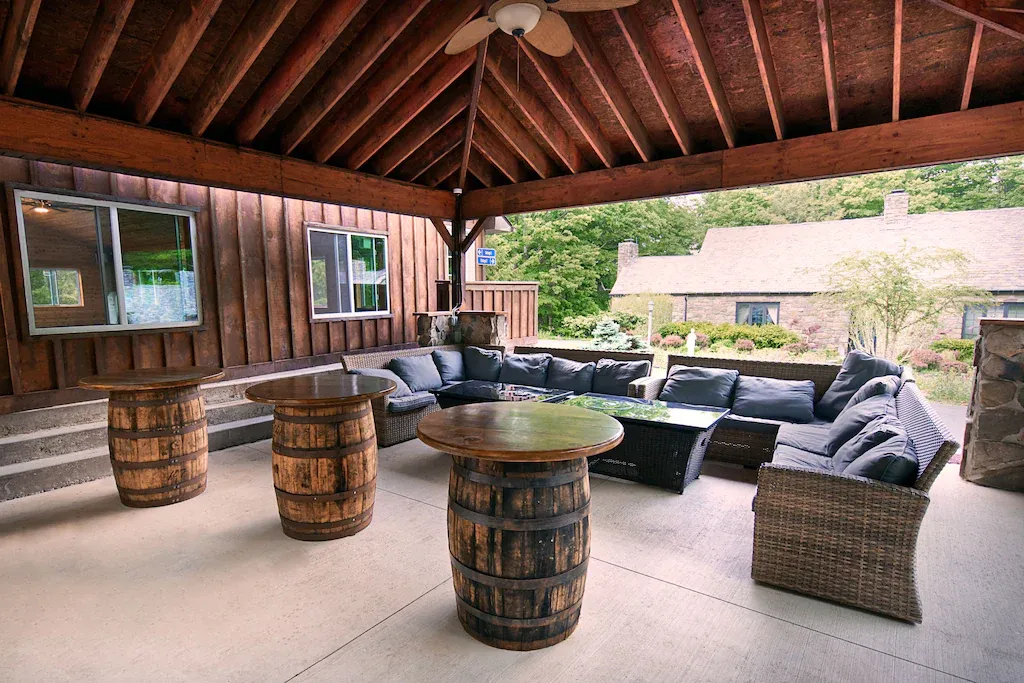 A patio with a table made out of barrels and a ceiling fan