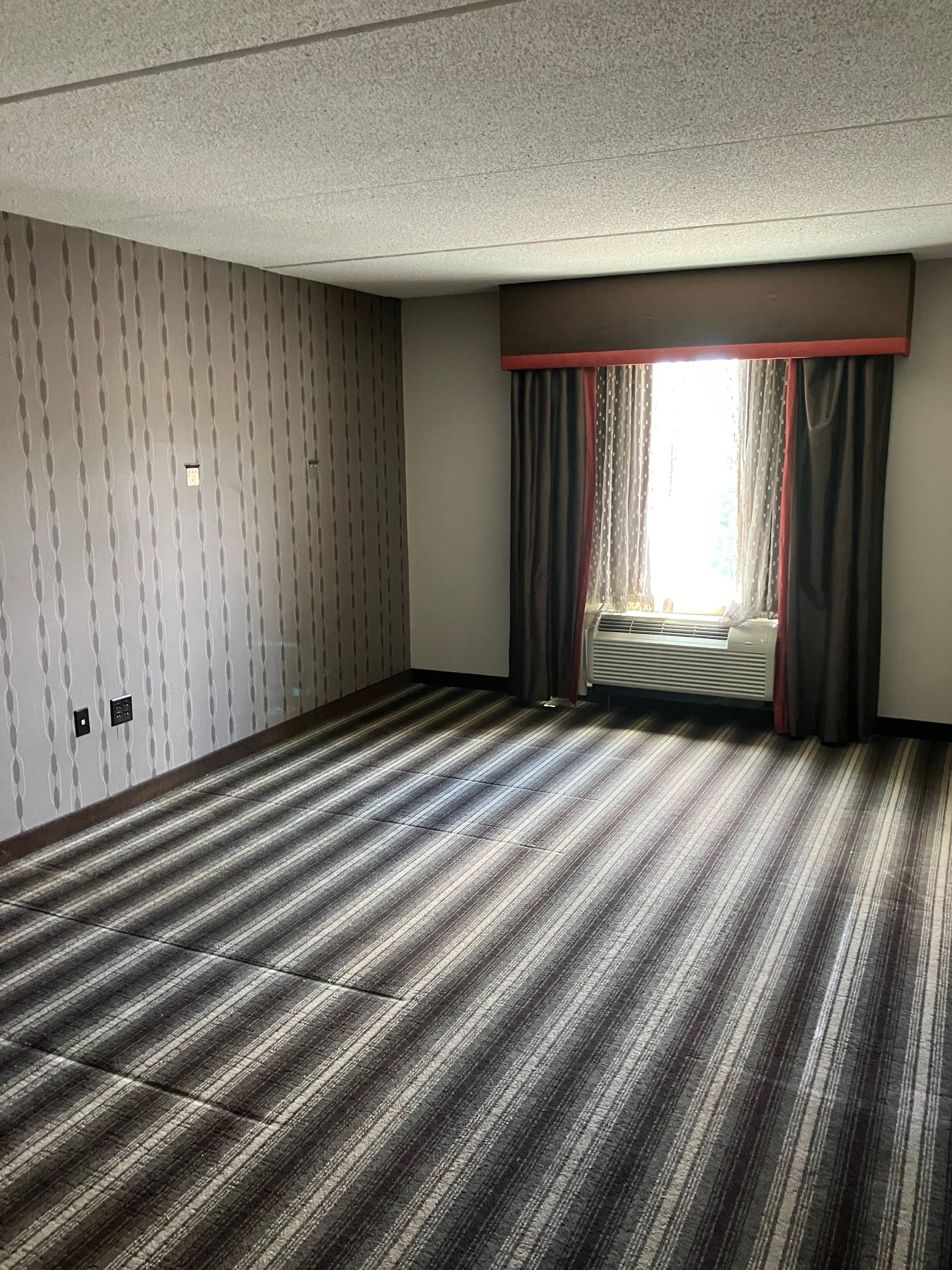Empty room with gray striped accent wall, gray carpet, and white ceiling.
