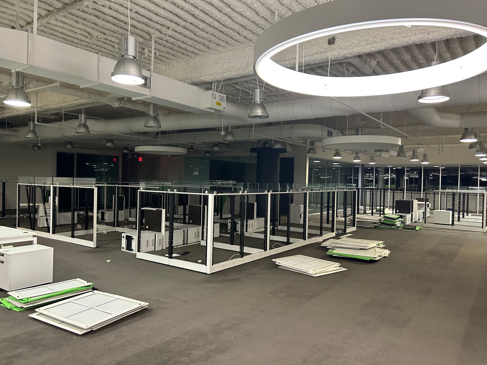 Office space with rows of desks, lights, and materials on the floor.