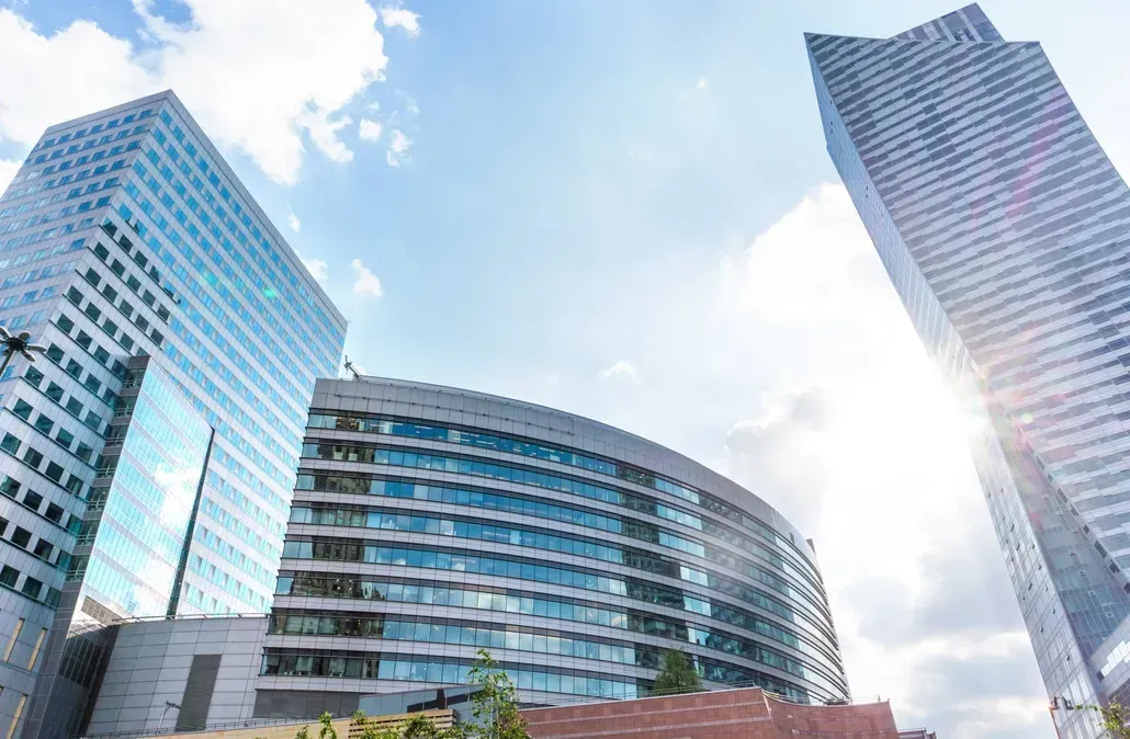 Skyscrapers against a bright blue sky. Modern buildings with glass facades, sunlight shining.