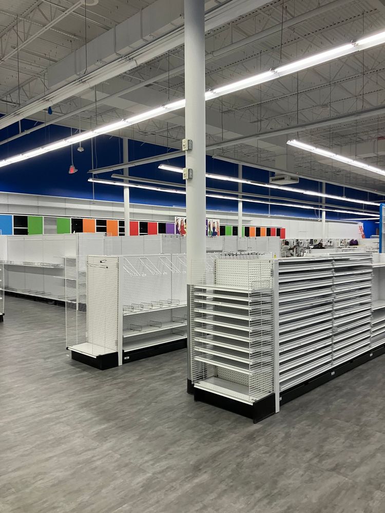 Interior of a store with white shelves, blue and colorful accent walls, and gray flooring.