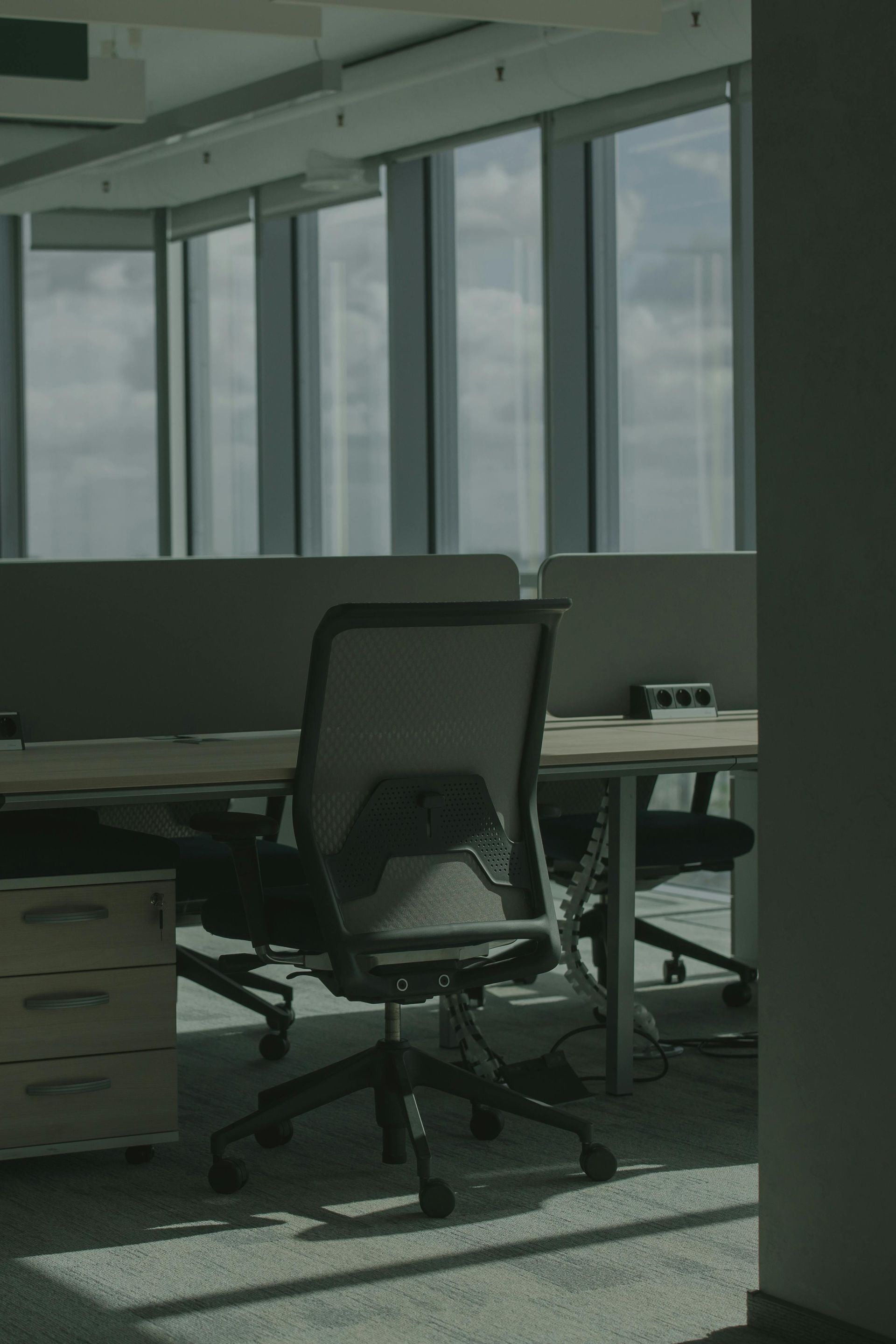 Conference room with long white table, black chairs, frosted glass wall, TV, and phone.