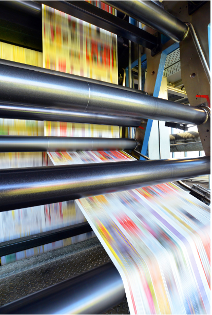 Printing press in action, producing color publications; rolls of paper move rapidly.