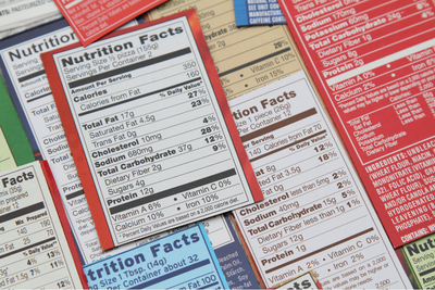Assorted nutrition facts labels stacked and overlapping in red, white, and blue packaging