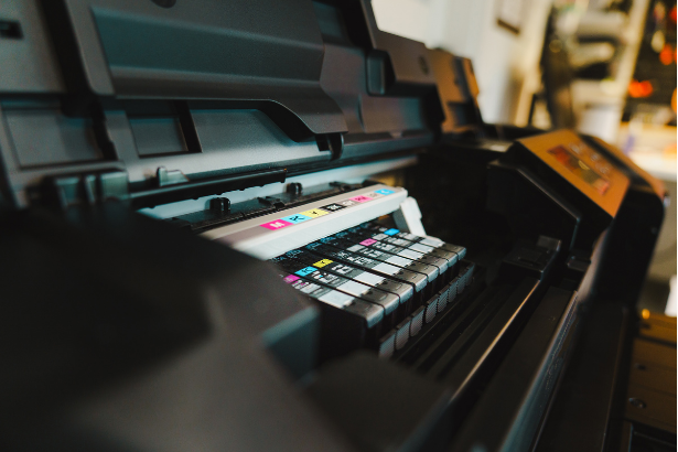 Close-up of a wide-format printer with visible ink cartridges in multiple colors.