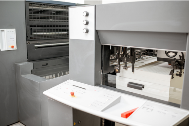 Offset printing press, gray with white accents, printing paper.