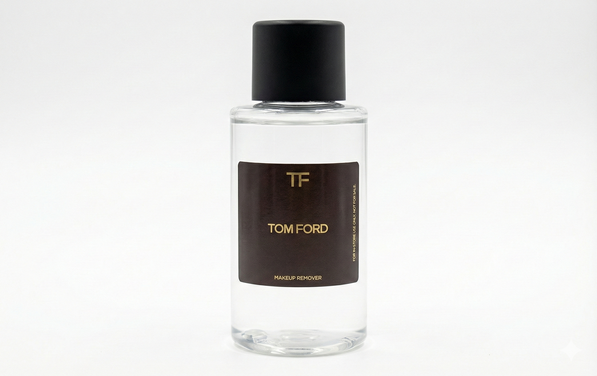 A clear, cylindrical perfume bottle with a black cap and a dark label reading 