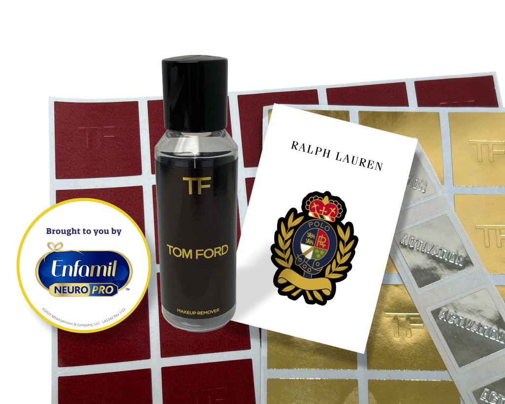 A Tom Ford fragrance bottle stands among various branding stickers, including Enfamil and Ralph Lauren logos.