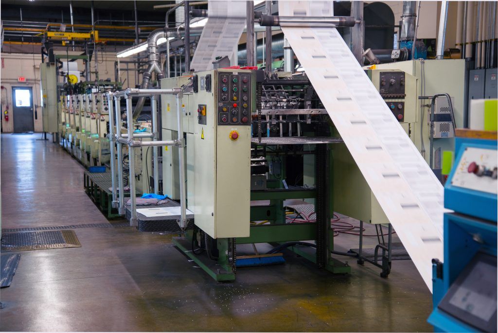 Printing press in factory, printing continuous paper, control panel, beige and blue.