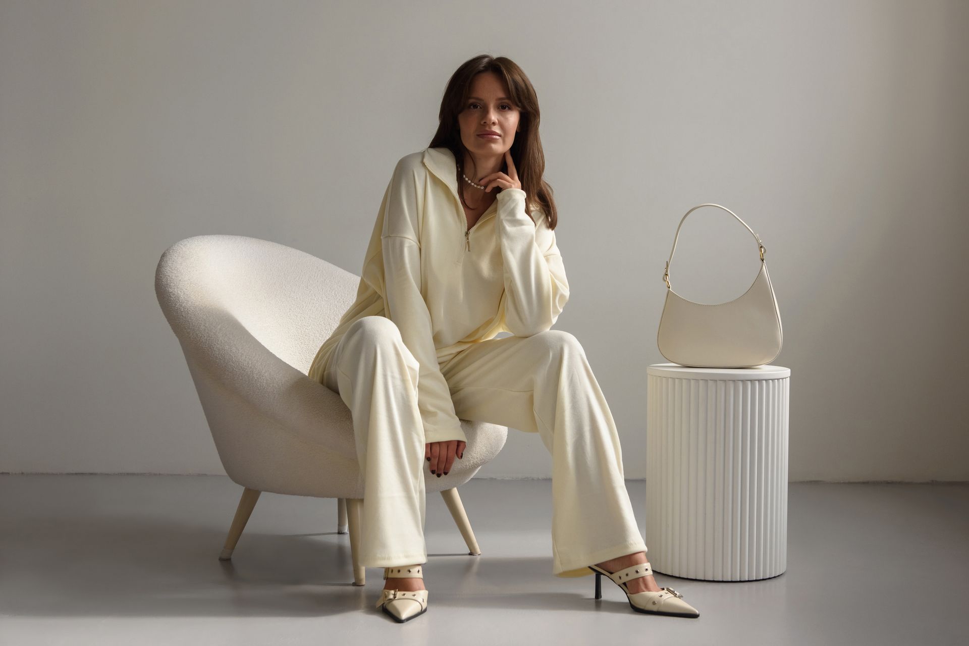 Una donna in abito bianco è seduta su una sedia bianca.