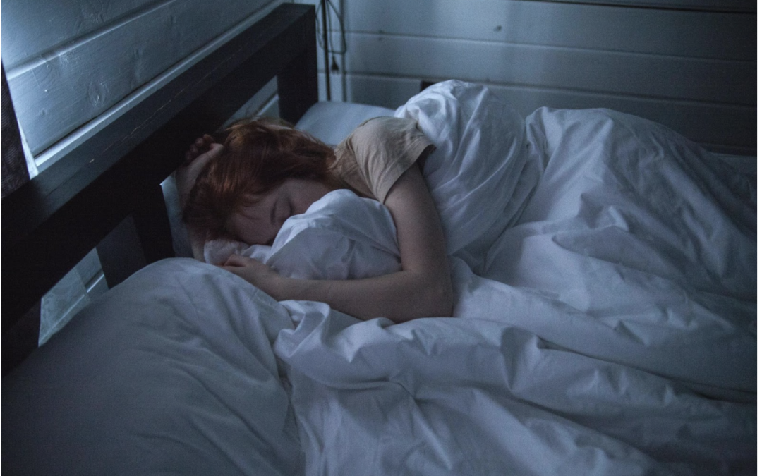 A woman is sleeping in a bed with white sheets and pillows.
