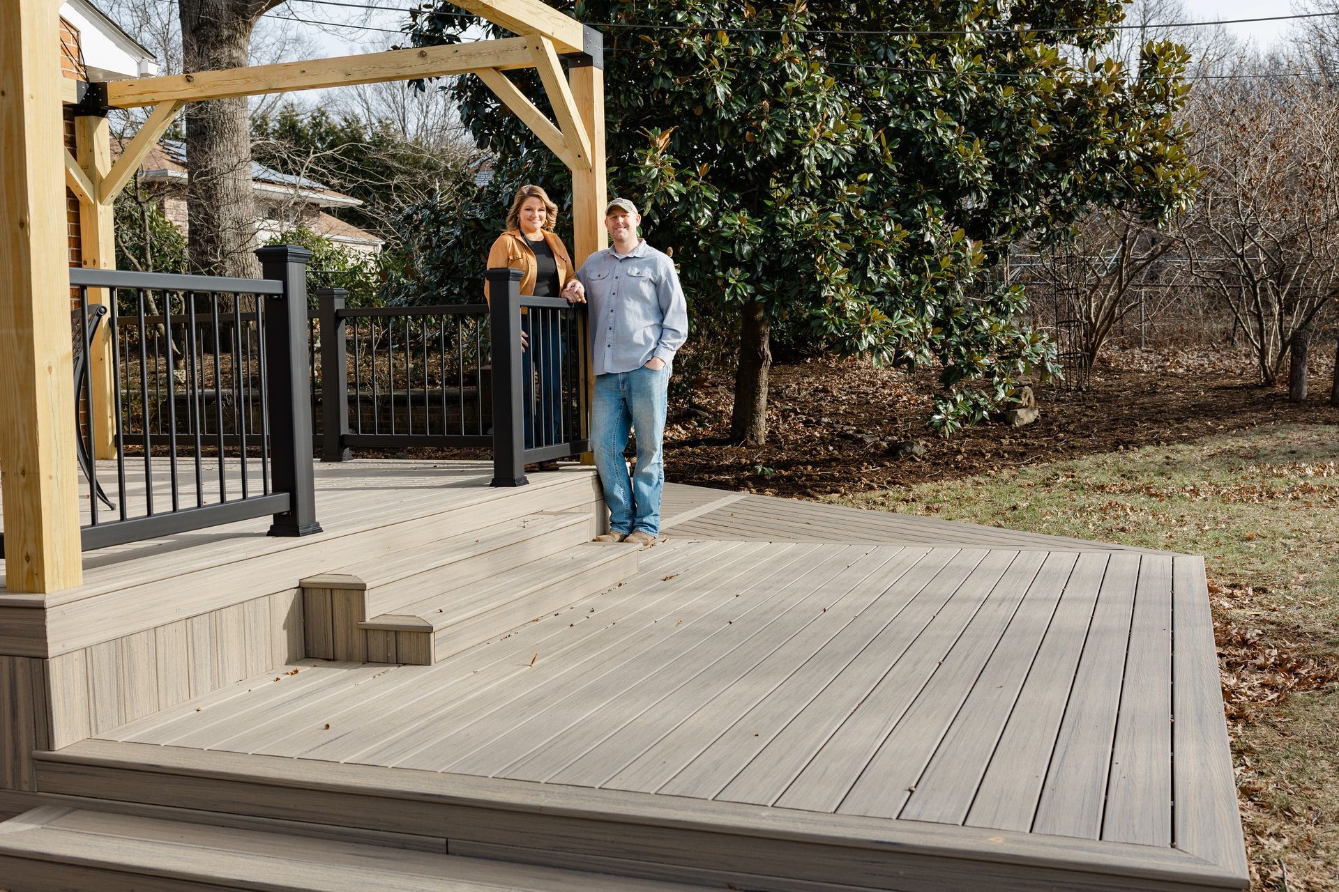 A spacious outdoor patio with a stone fireplace, wicker furniture, and tall tables under a covered roof.