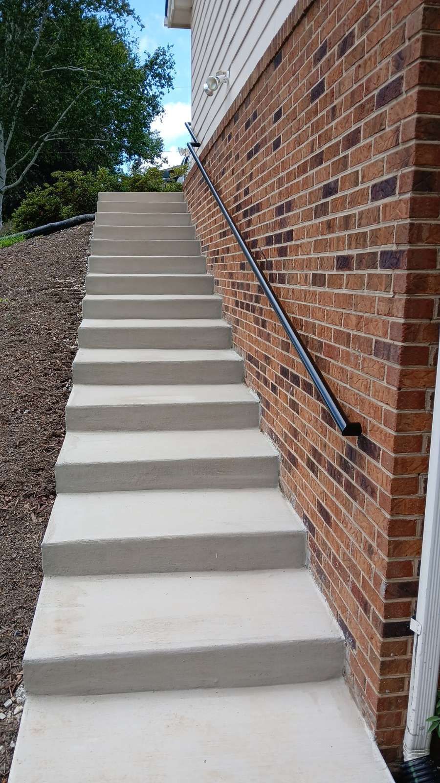 A low-angle view of a triangular roof structure with reddish-brown metal beams and a bright sky at the apex.