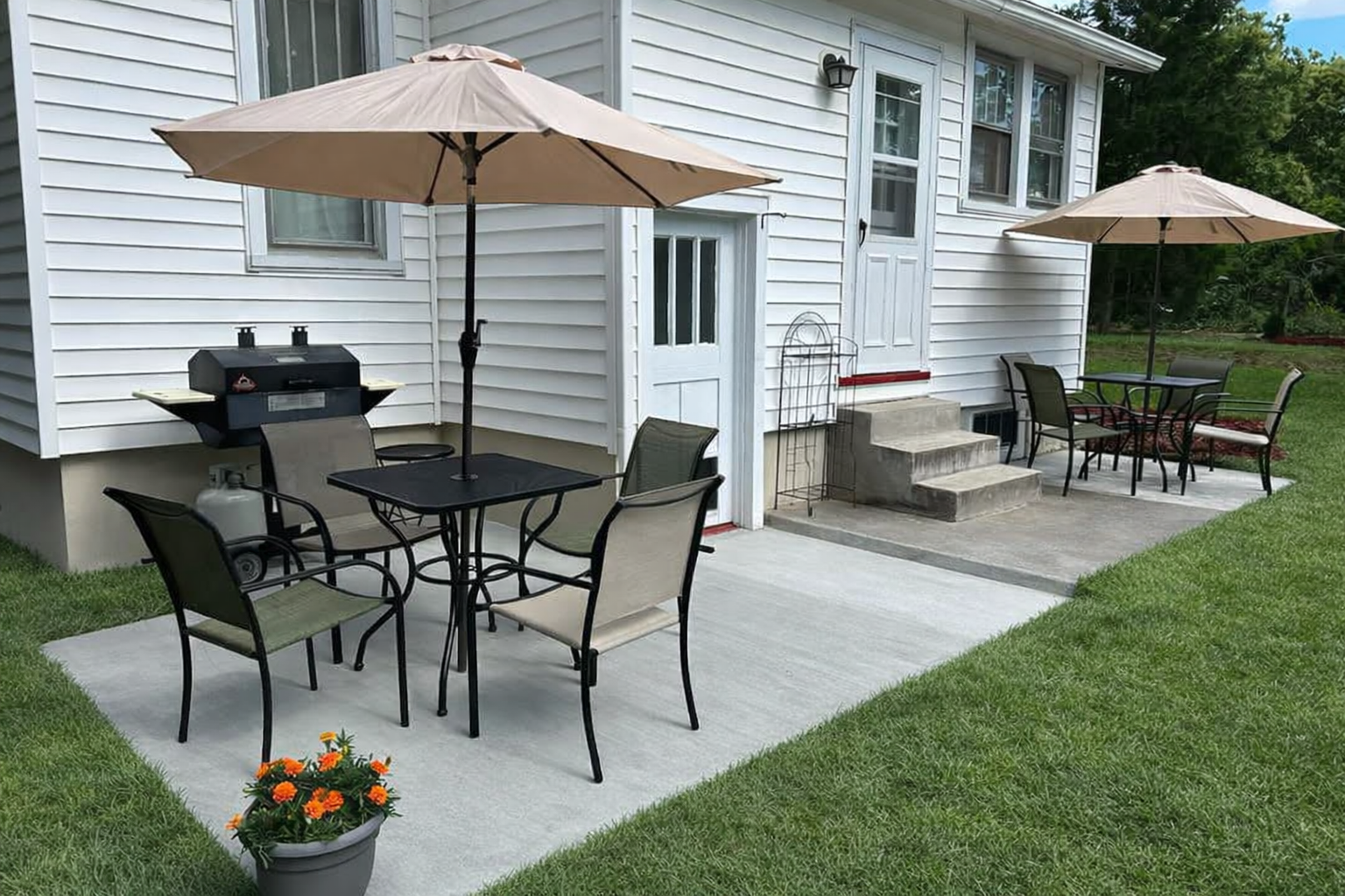 A wooden deck with built-in bench seating beside a white house in a grassy yard.