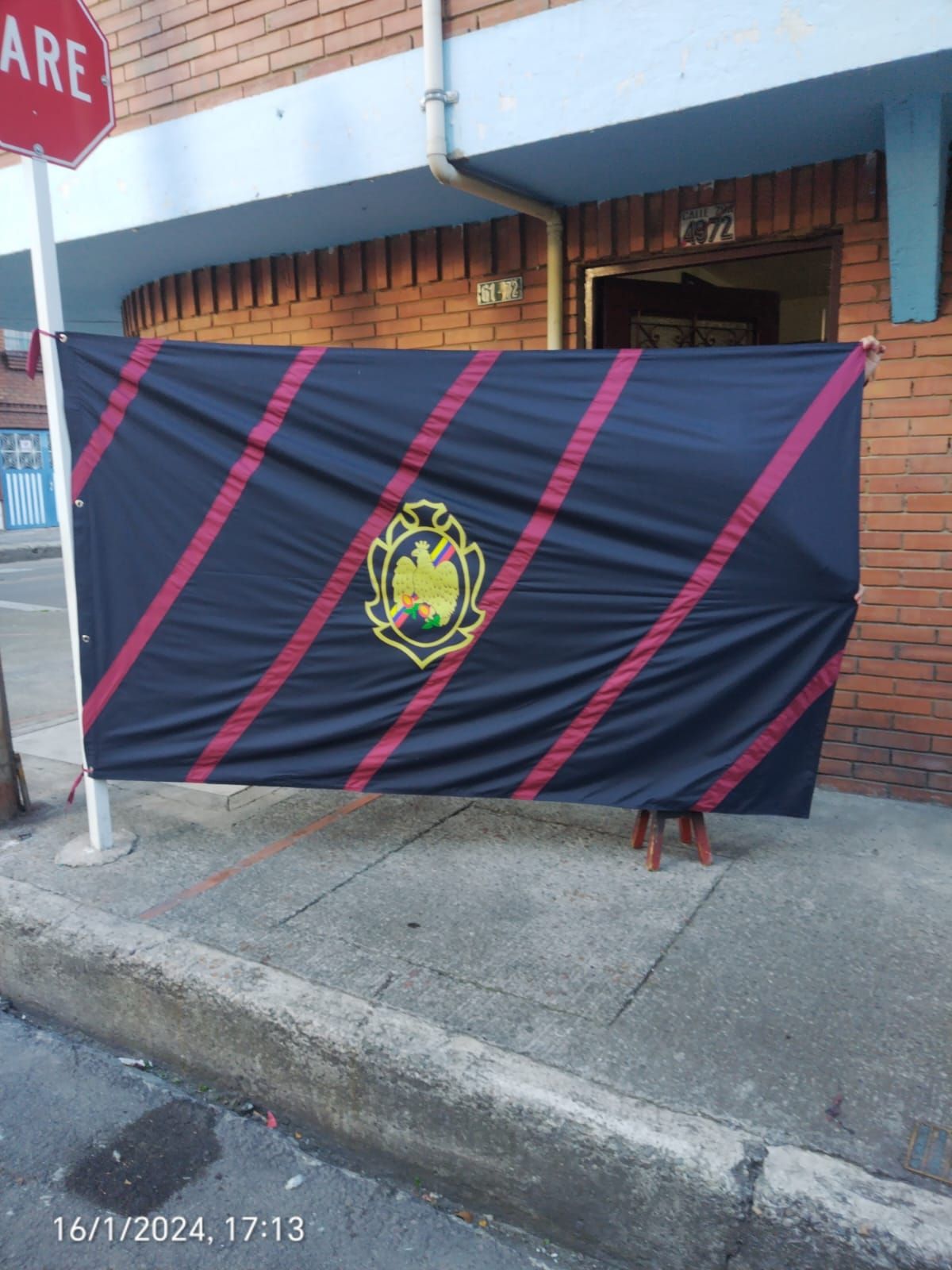 Una gran bandera cuelga en la acera frente a una señal de alto