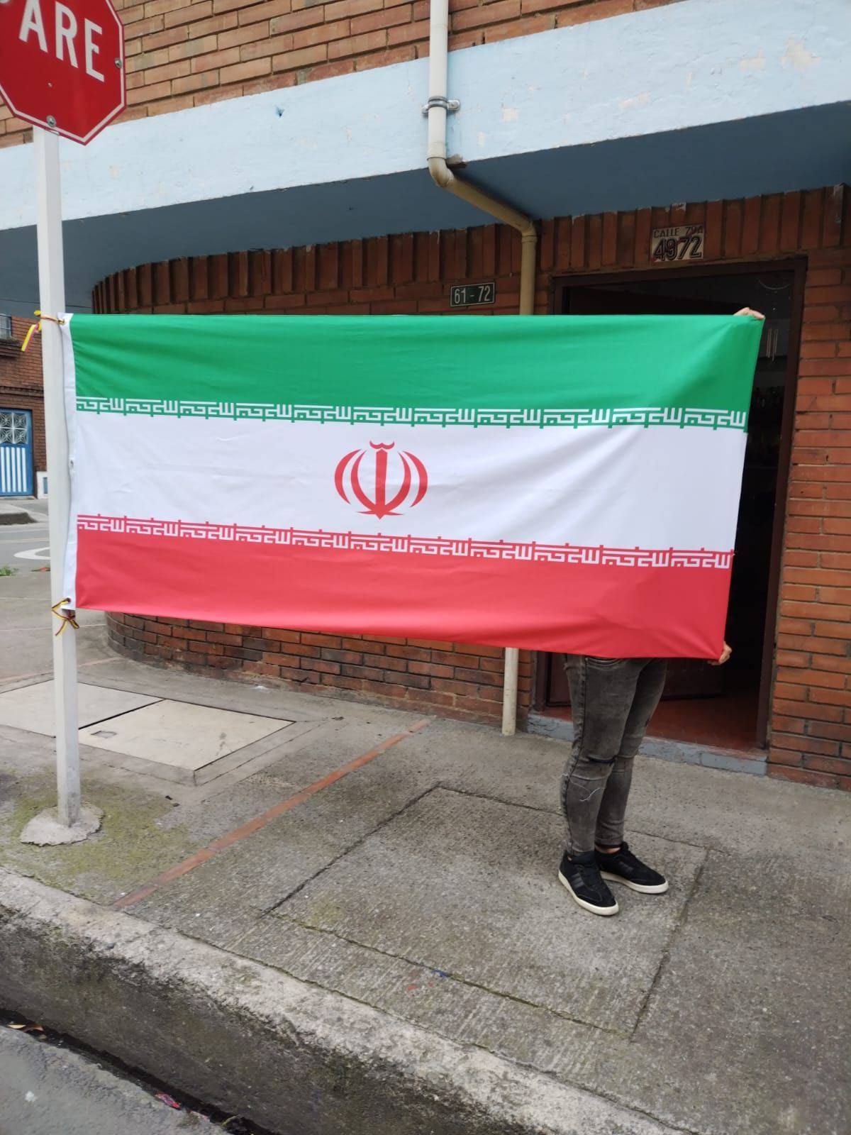 Una persona sostiene una bandera frente a una señal de alto.