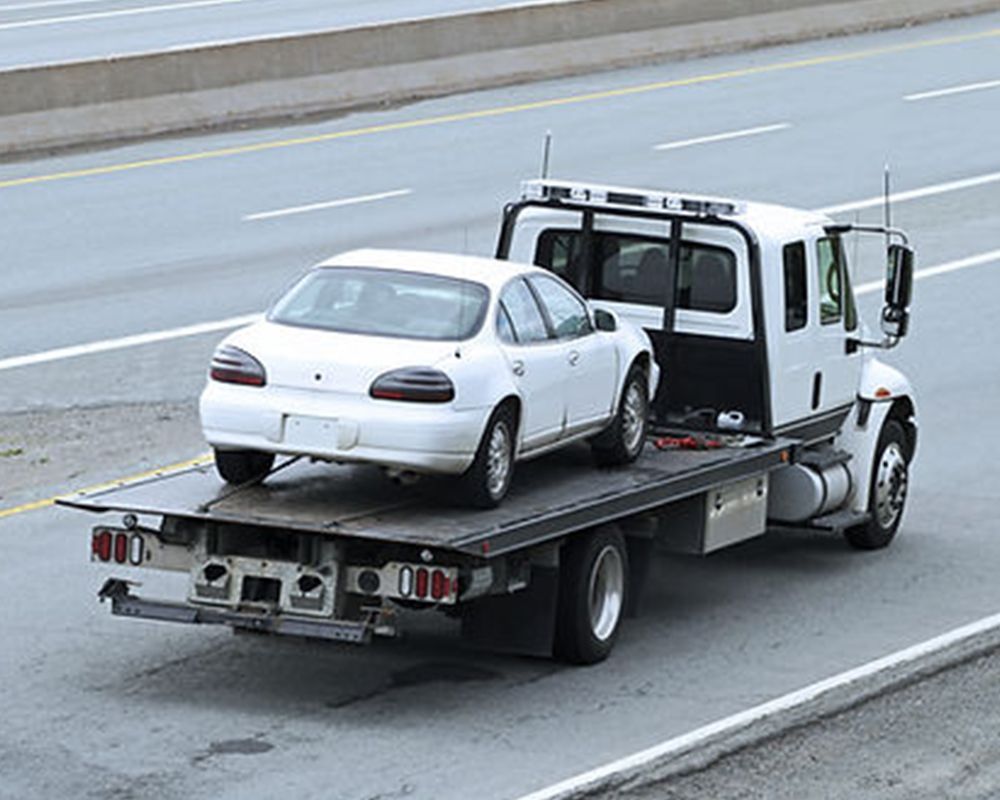 White Car is Being Towed by a Tow Truck