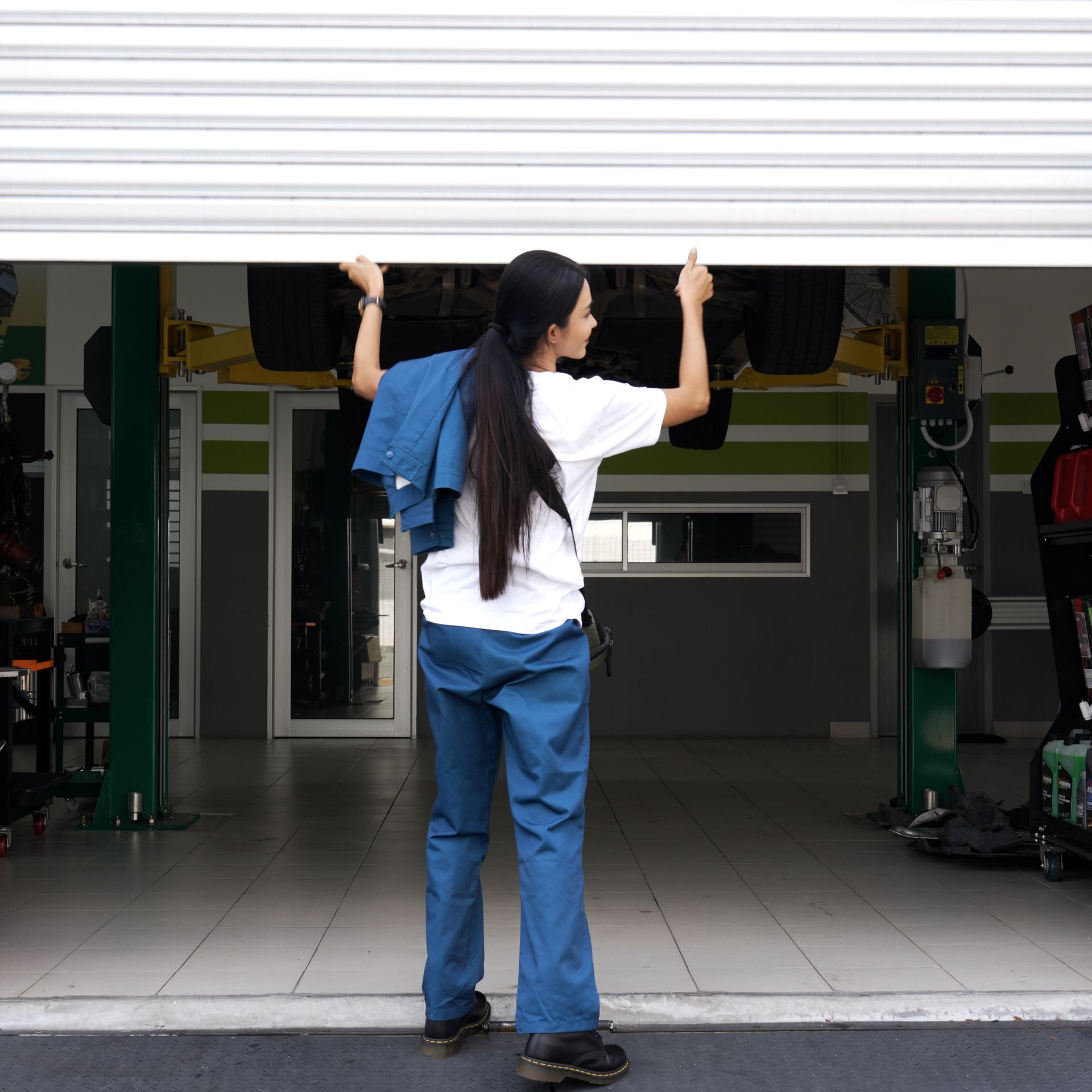 A woman in blue pants is opening a garage door