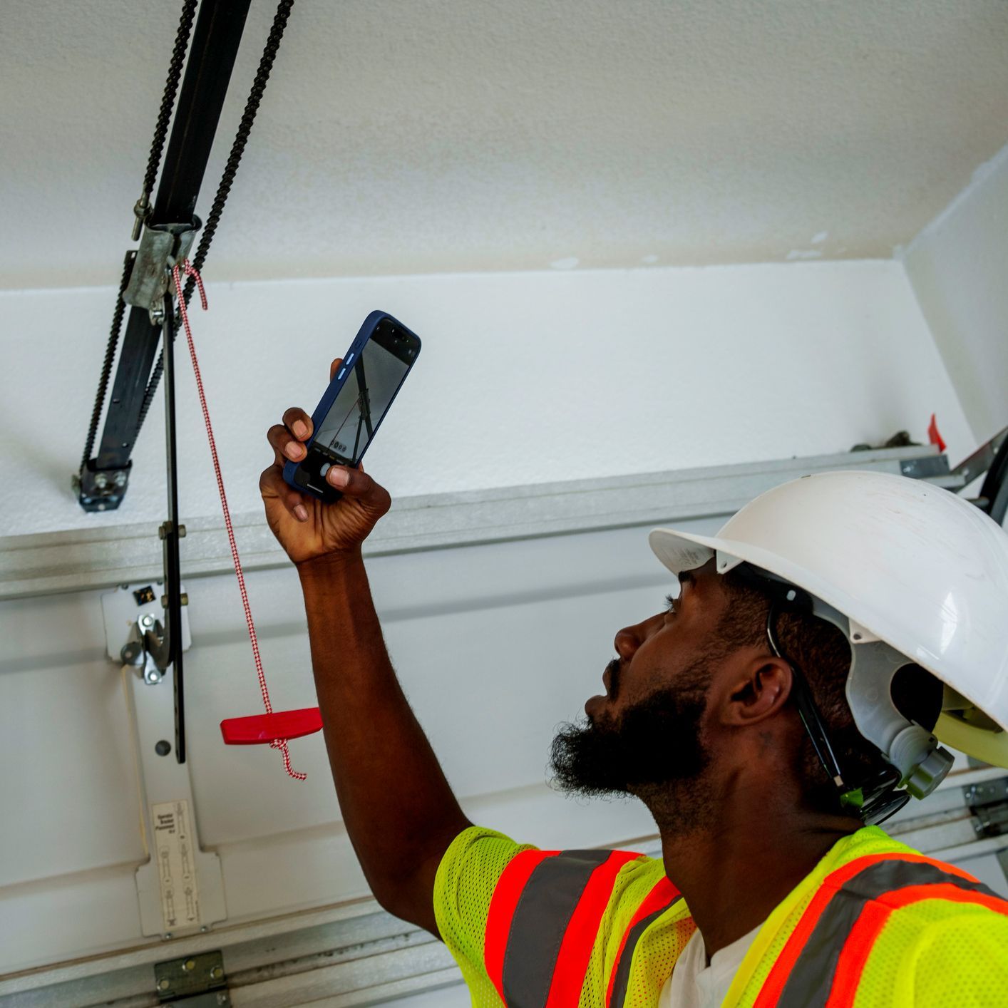 A man taking a picture of a garage door with his phone