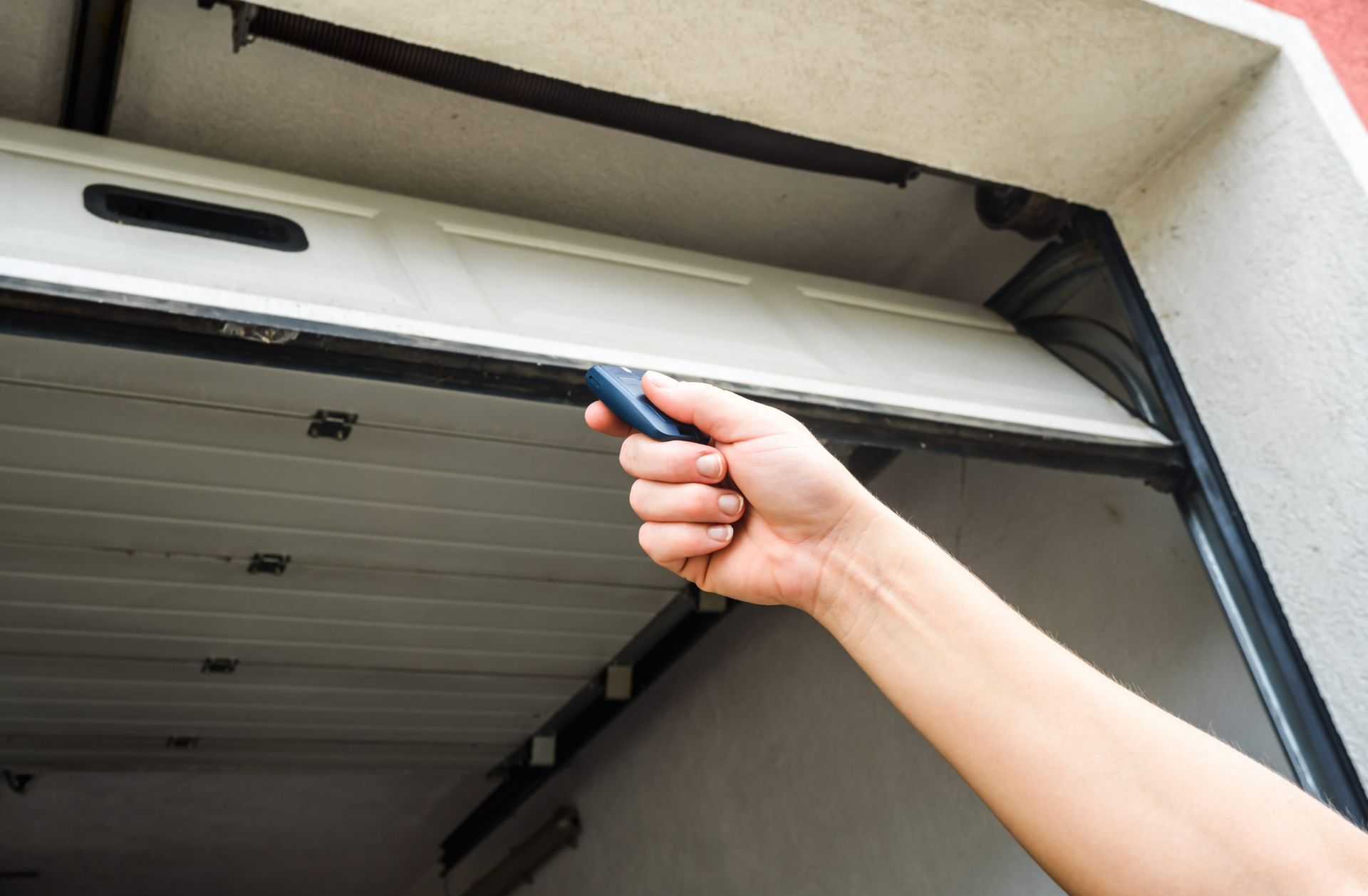 A person is opening a garage door with a remote control.