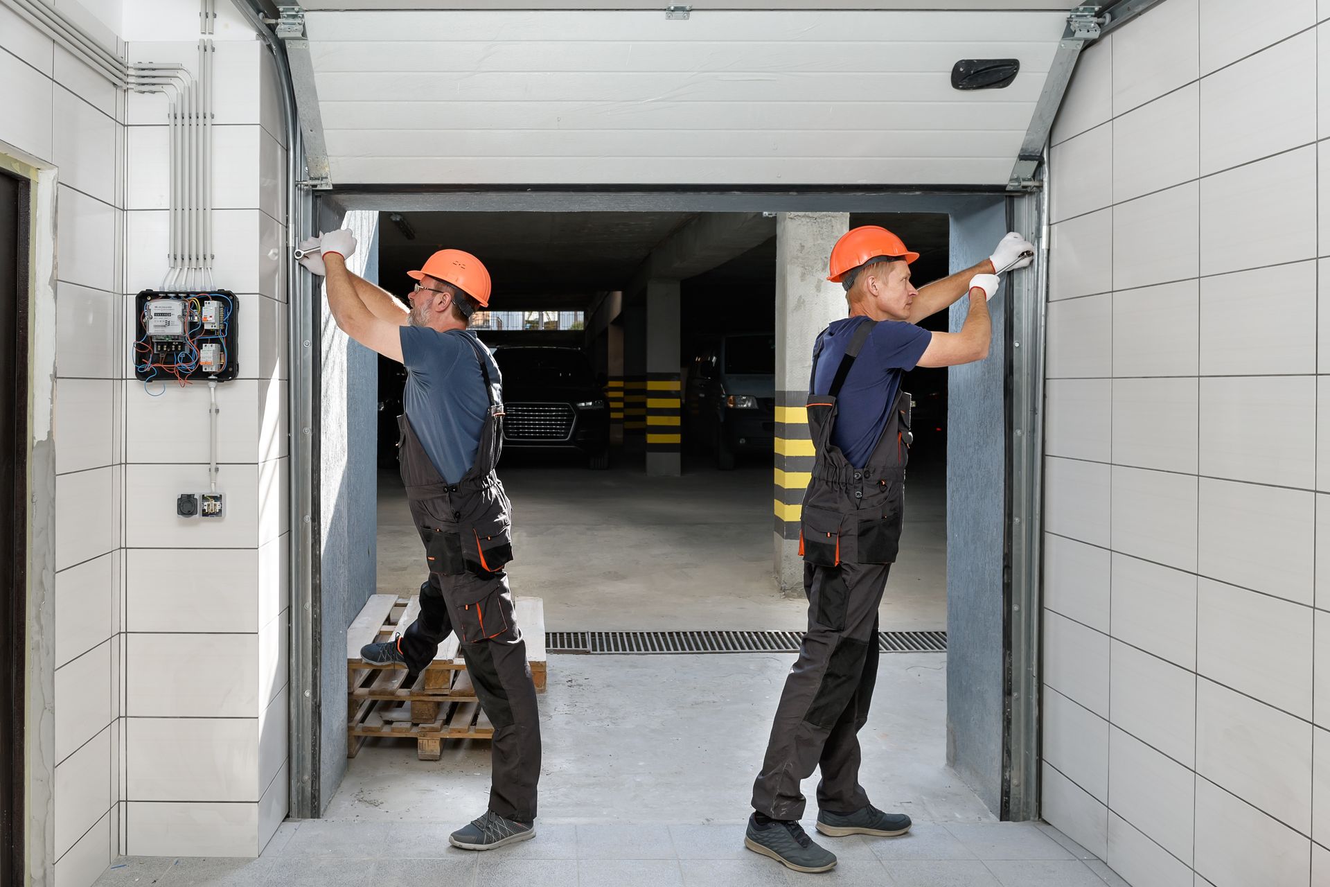 Two men are working on a garage door.