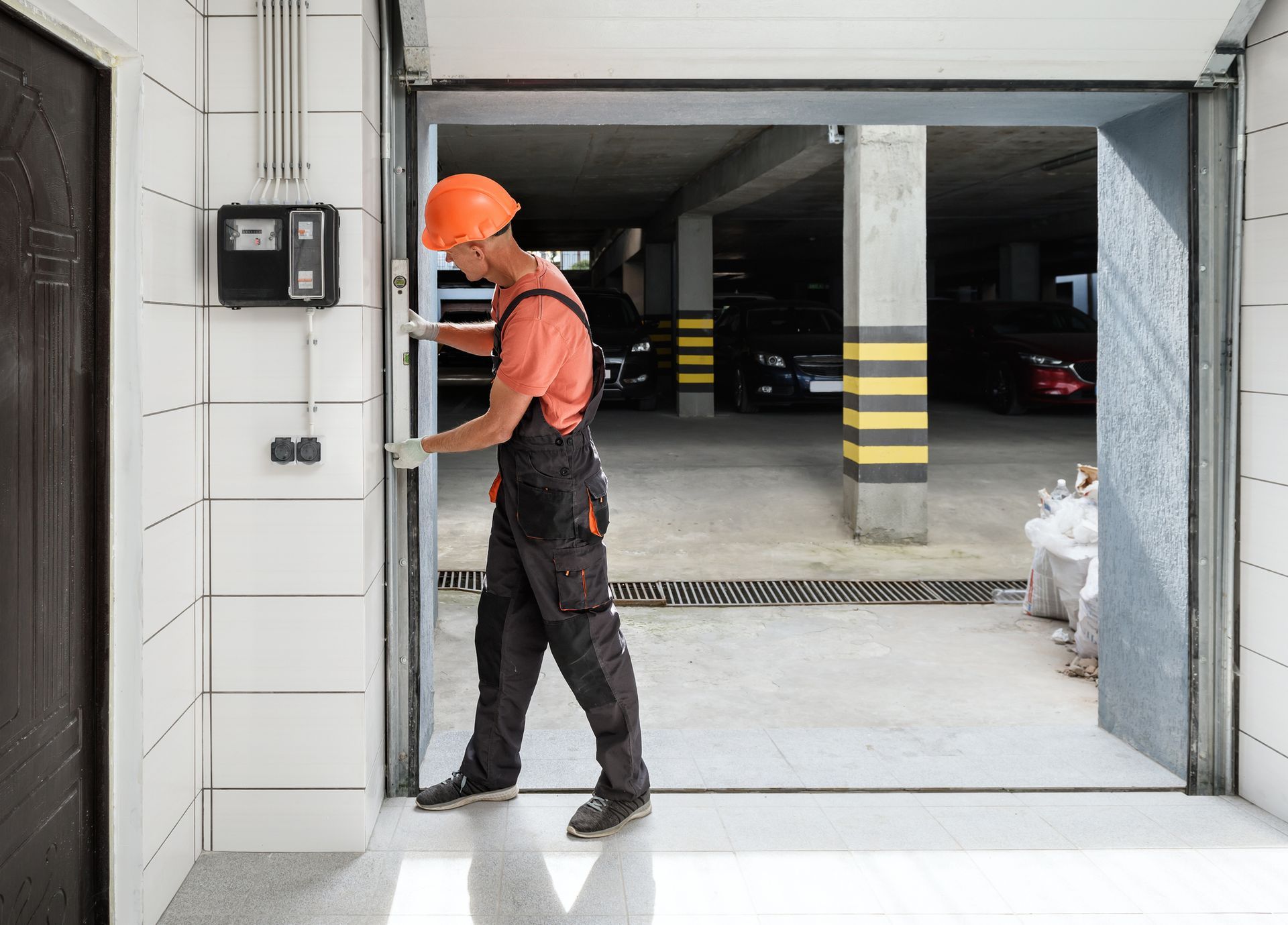 A man is opening a garage door in a parking garage.