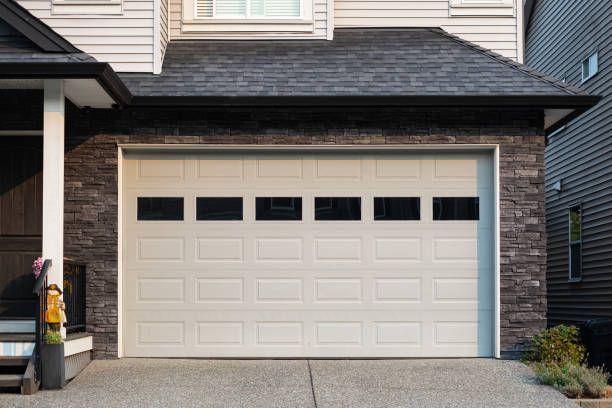 A white garage door is sitting in front of a brick house.