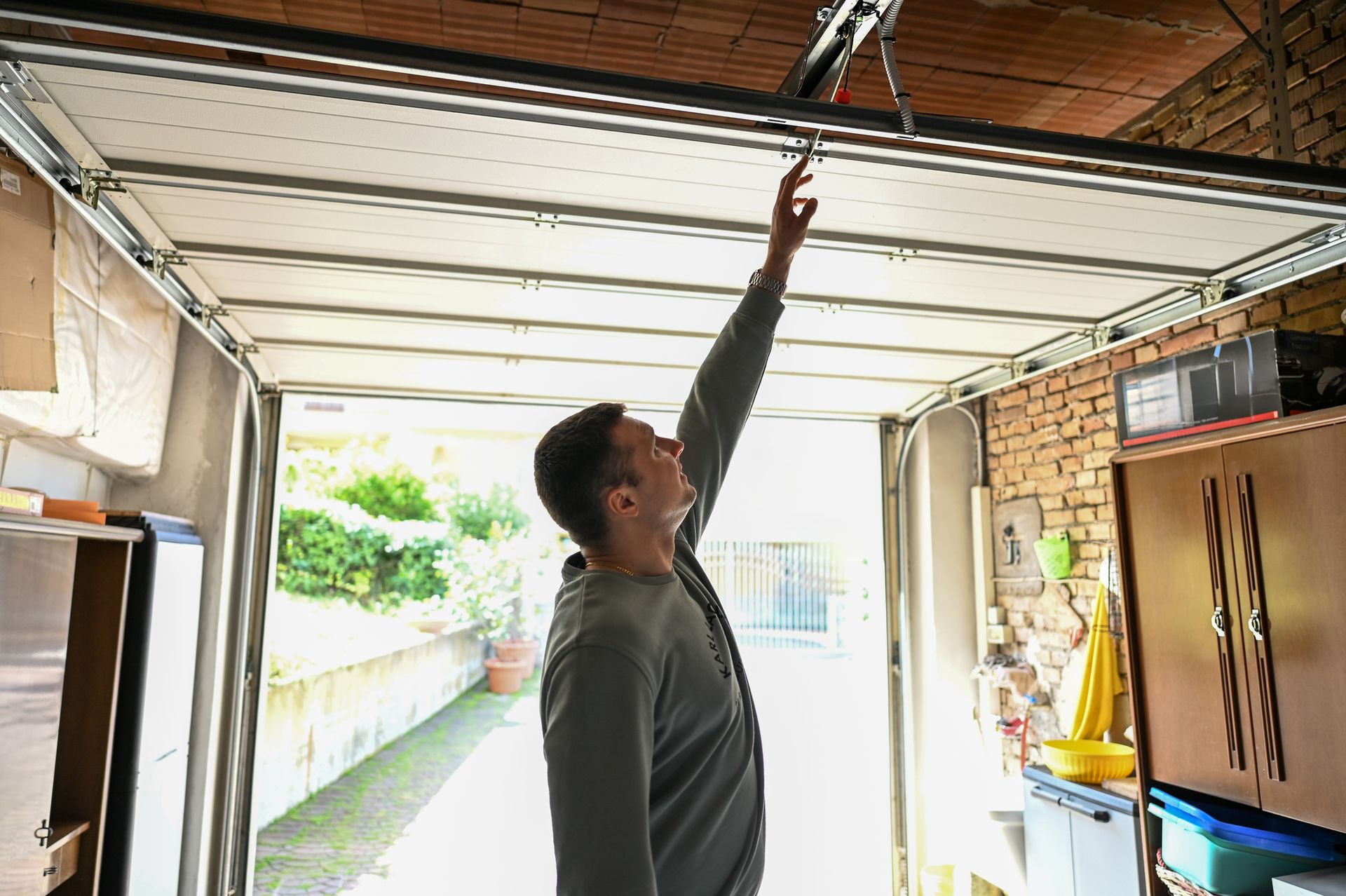 A man is looking up at the ceiling of a garage door.