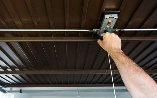 A man is using a pulley to lift a garage door.
