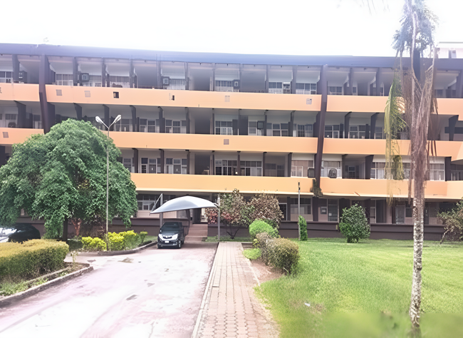 Multi-story orange building with many windows, a grassy area, and trees.
