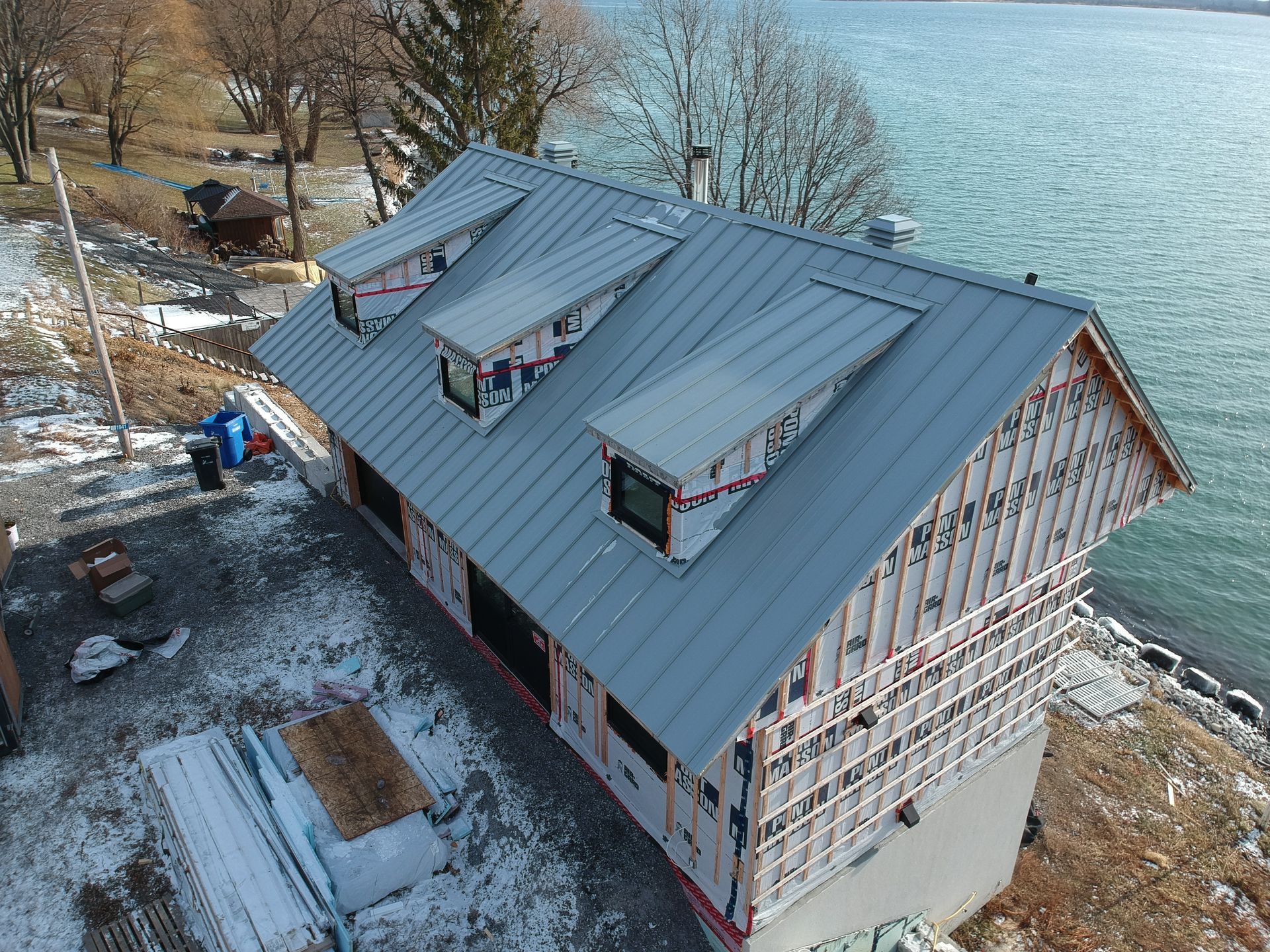 An aerial view of a house under construction next to a body of water.