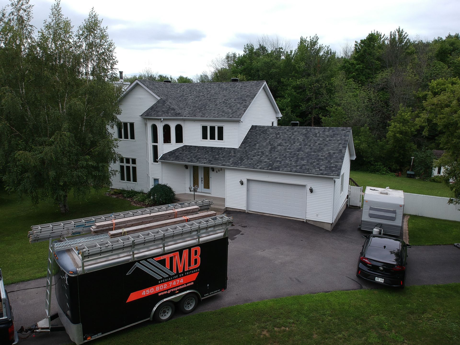 An aerial view of a house with a trailer parked in front of it.