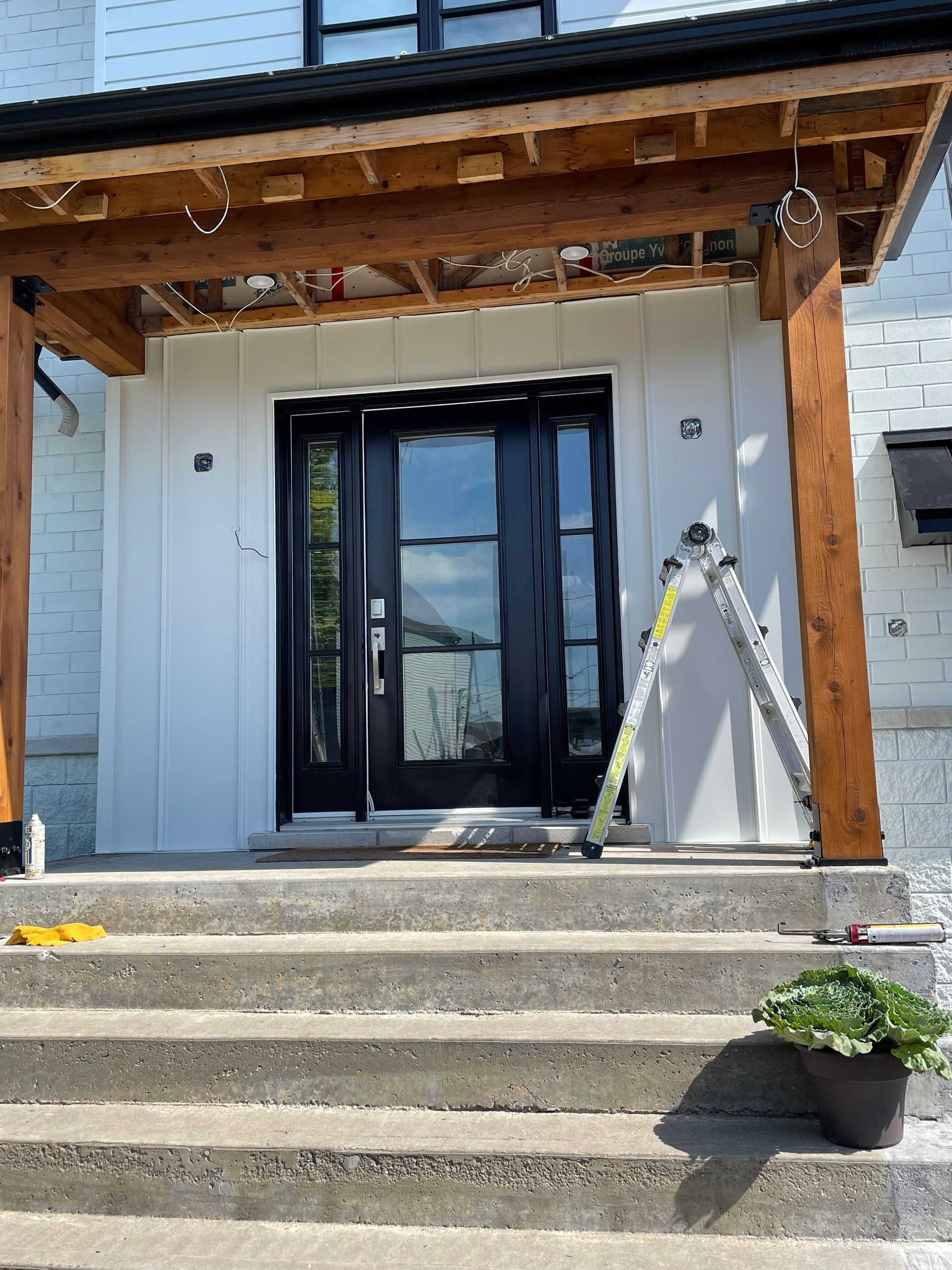 A white house with black doors and a wooden porch.