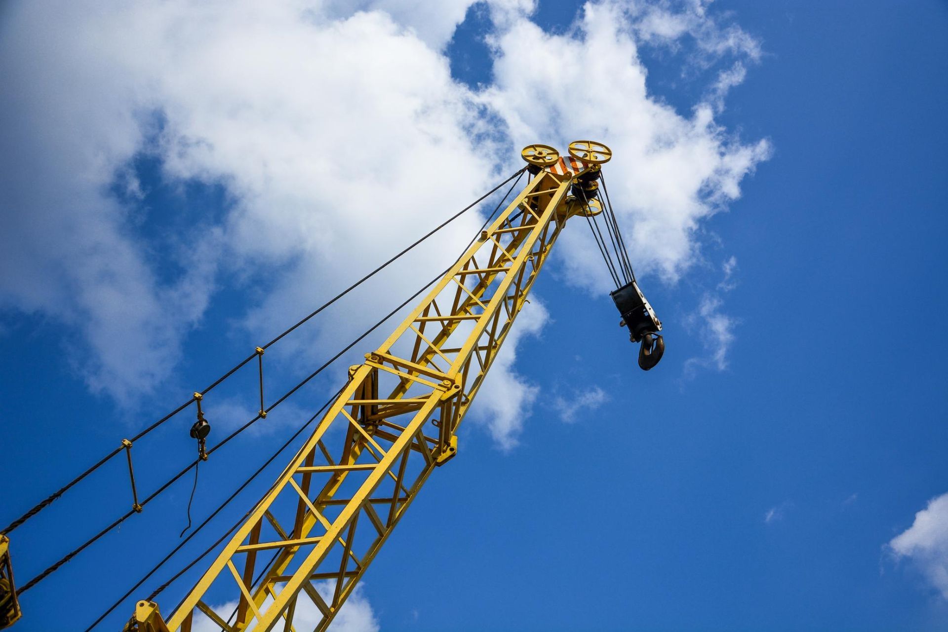 Yellow crane arm against a blue sky with white clouds.