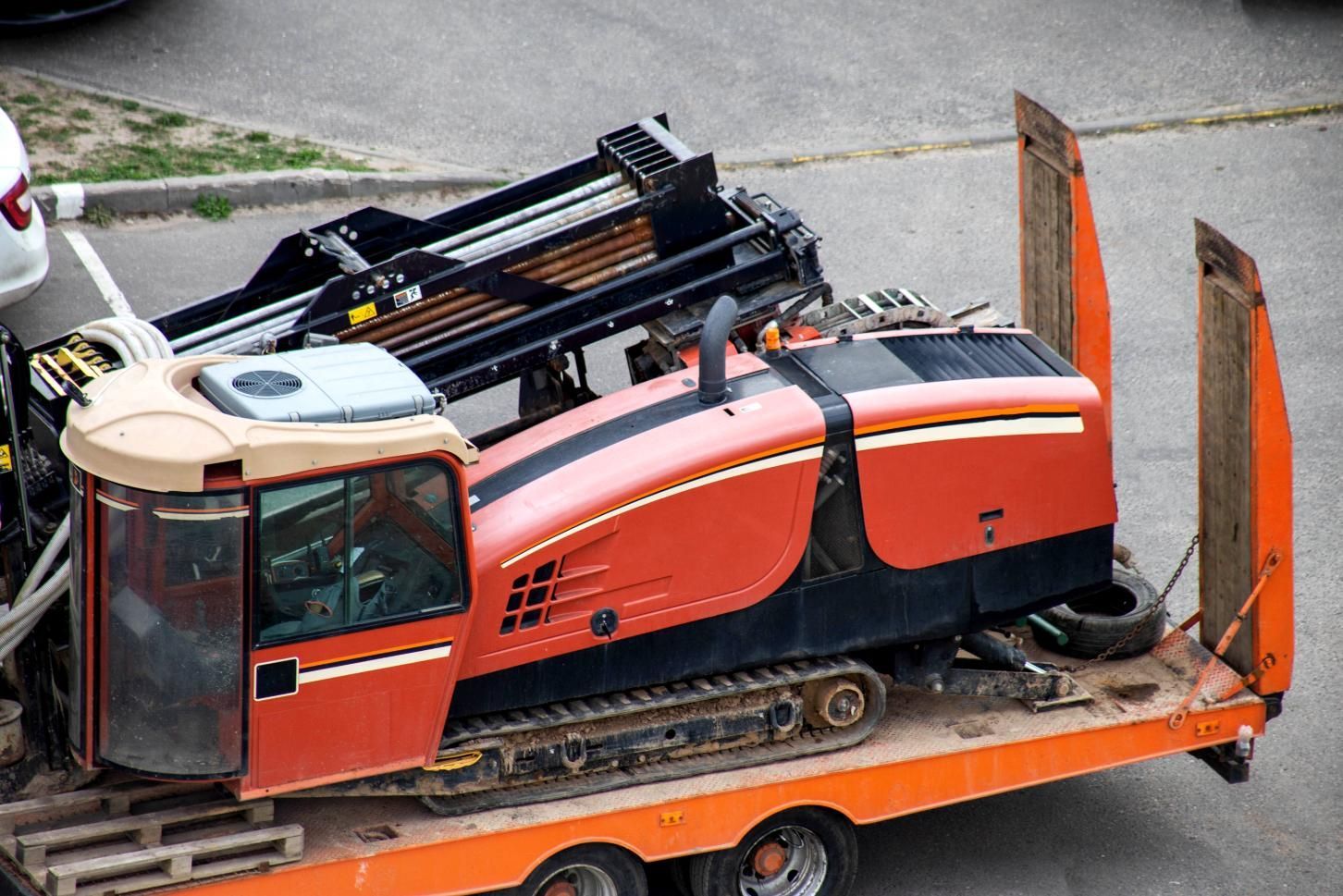 Orange and black horizontal drilling machine on a flatbed trailer, parked outdoors.