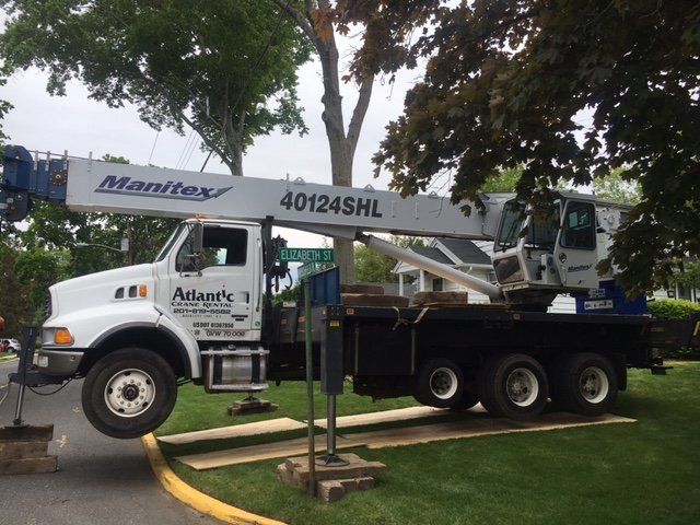 White crane truck removing a tree in a residential area.