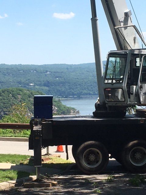 Crane with cab in front of a river and green hills.