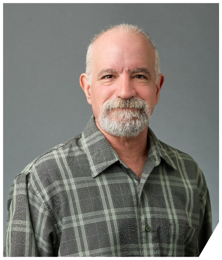 A man in a blue suit and white shirt is smiling for the camera.