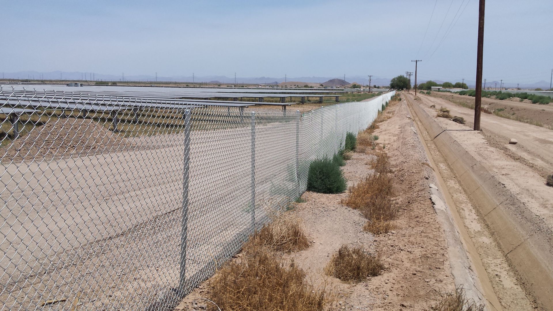 A metal fence is surrounding an empty parking lot.