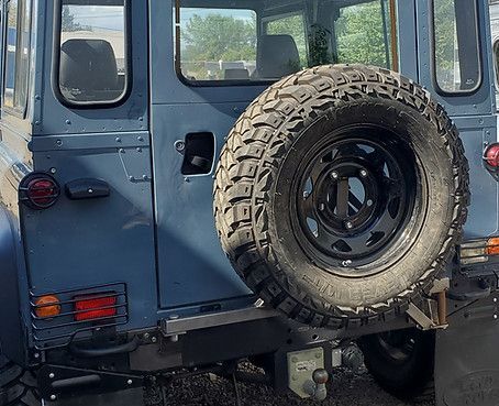 Blue off-road vehicle rear with a spare tire mounted on the back.