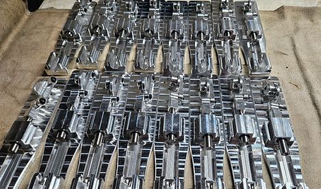 Rows of shiny metal pipes and fittings laid out on a tan floor mat.