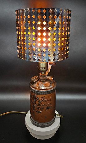 Copper-toned lamp with patterned shade, lit warmly on a white base against a dark background