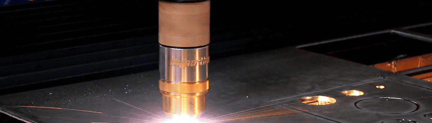 Industrial cutting torch slicing metal with bright sparks in a dark workshop.