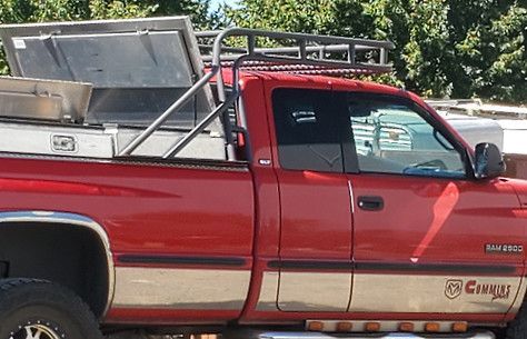 Red pickup truck with a ladder rack and cargo in the bed, parked outdoors.