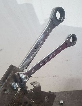 Two shiny metal levers with circular ends attached to a mechanical base against a white background