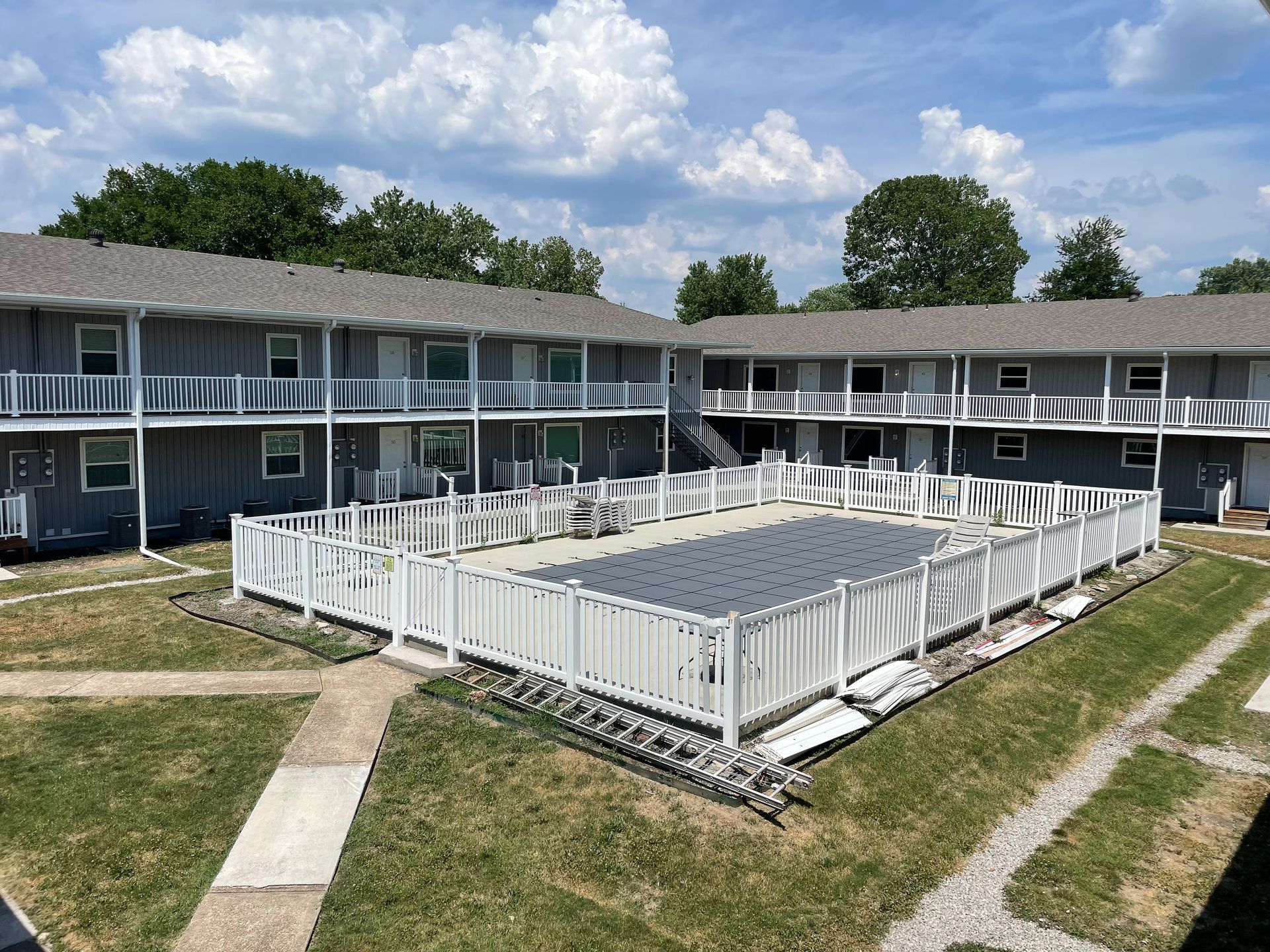 Apartment complex with a central fenced pool area and a cloudy sky overhead