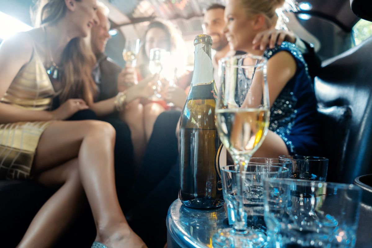 A group of people are sitting in a limousine drinking champagne.