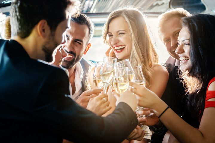 A group of people are toasting with champagne glasses in a limousine.