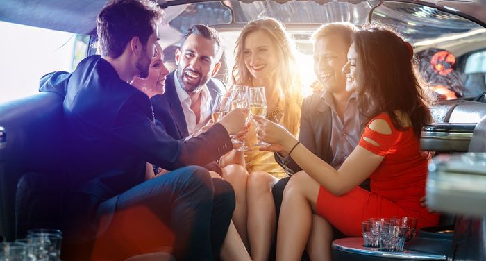 A group of people are sitting in a limousine toasting with champagne.